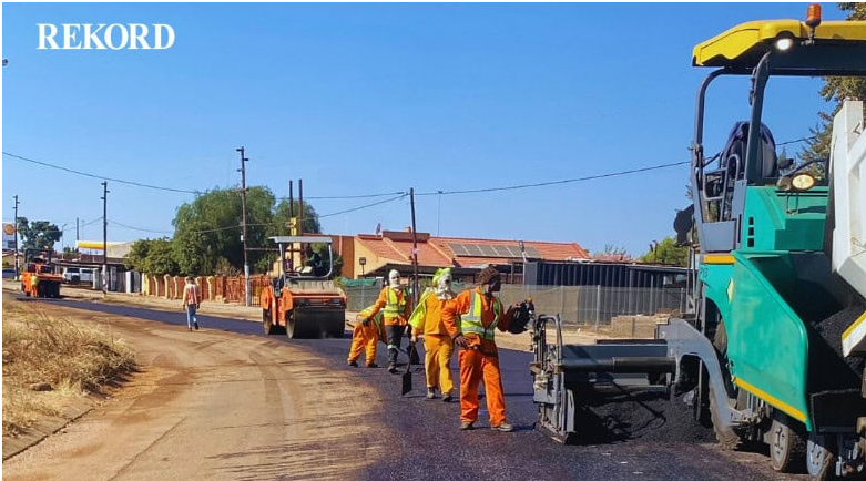 A paving machine lays fresh asphalt on a street.