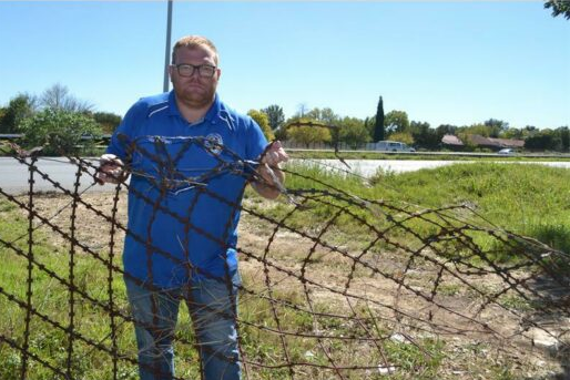 Ward 92 Clr Kade Guerreiro holds a piece of the broken fence that lies along the ground between the R24 westbound and Herman Street. Behind him is the informal off-ramp made by motorists, near the intersection of Herman Street and Koornhof Road.