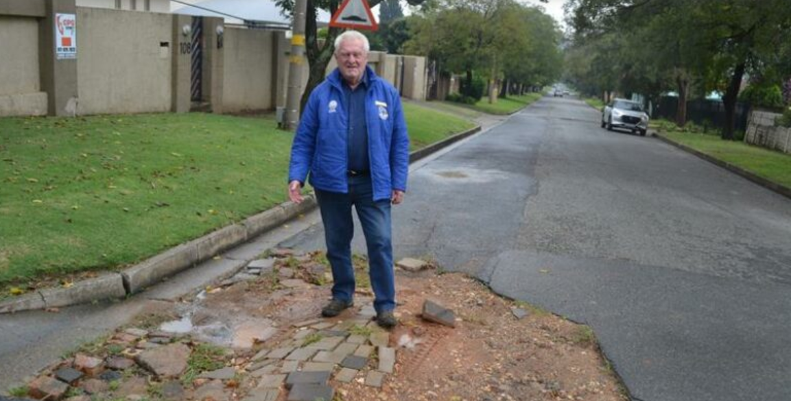  Ward 19 Ald Bill Rundle stands in one of the potholes along Third Avenue. 