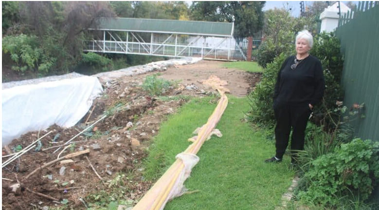 Fairland Estate resident Arlene Mania shows the crater next to her house. 