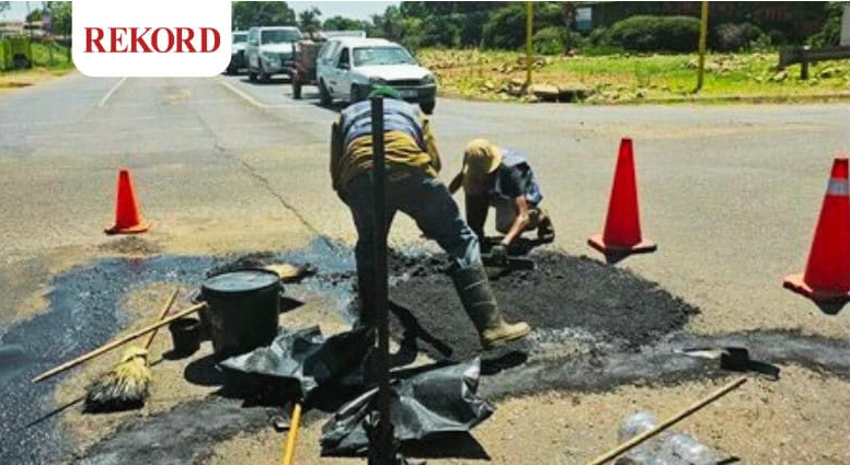 Workers repairing a pothole-riddled road.