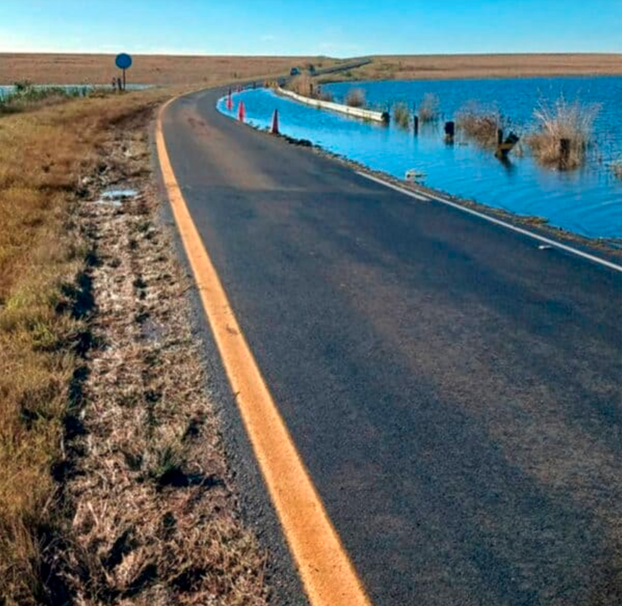 Floodwater overtops the Florence Dam crossing on the Warburton Road near Chrissiesmeer during flooding in April 2025. The image shows traffic cones placed along the submerged section of the roadway. 
