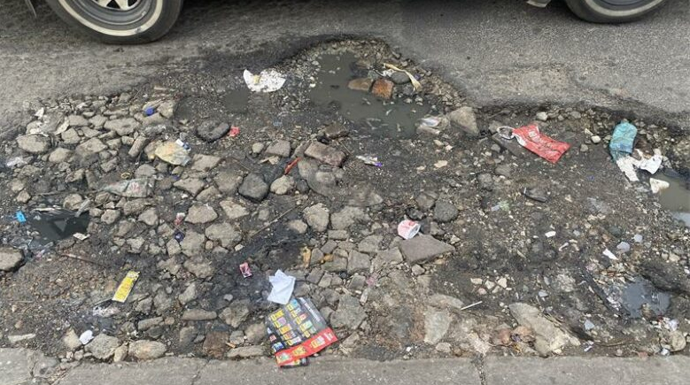 Cars avoid the unattended large pothole on Market Street. 