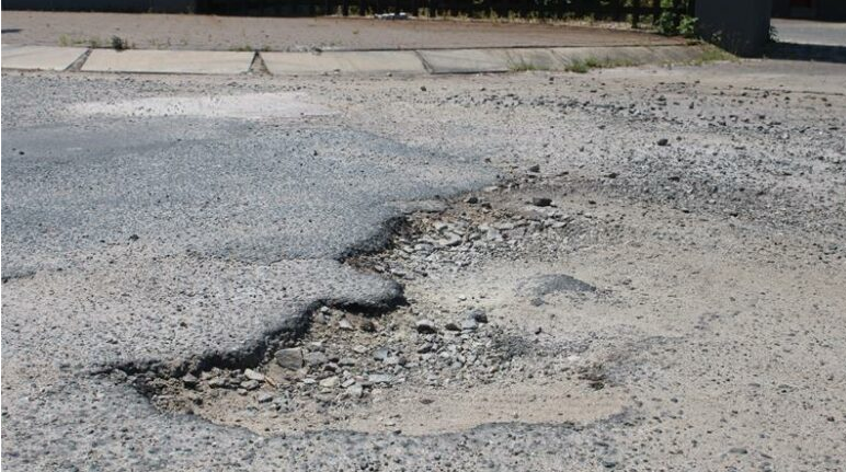 Crumbling tar and exposed gravel on Pendulum Road. 