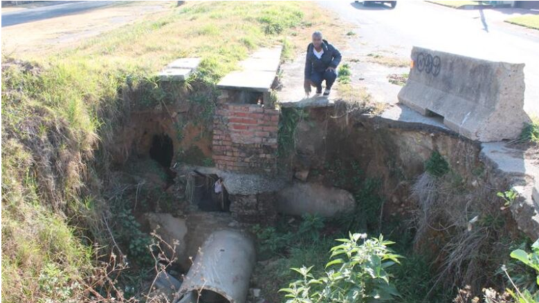  Caxton West Rand intern Zama Sithole shows the depth of the hole where the pavement collapsed due to erosion.