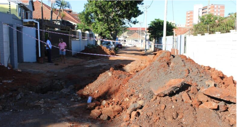  Two residents stand helpless, waiting for the unknown as the pile of sand and rocks remain in the middle of the road, in front of driveways. 